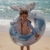 Chłopiec z kołem do pływania Ocean World 91cm Little Dutch na plaży – niebieskie koło z ogonem wieloryba i nadrukiem zwierząt morskich