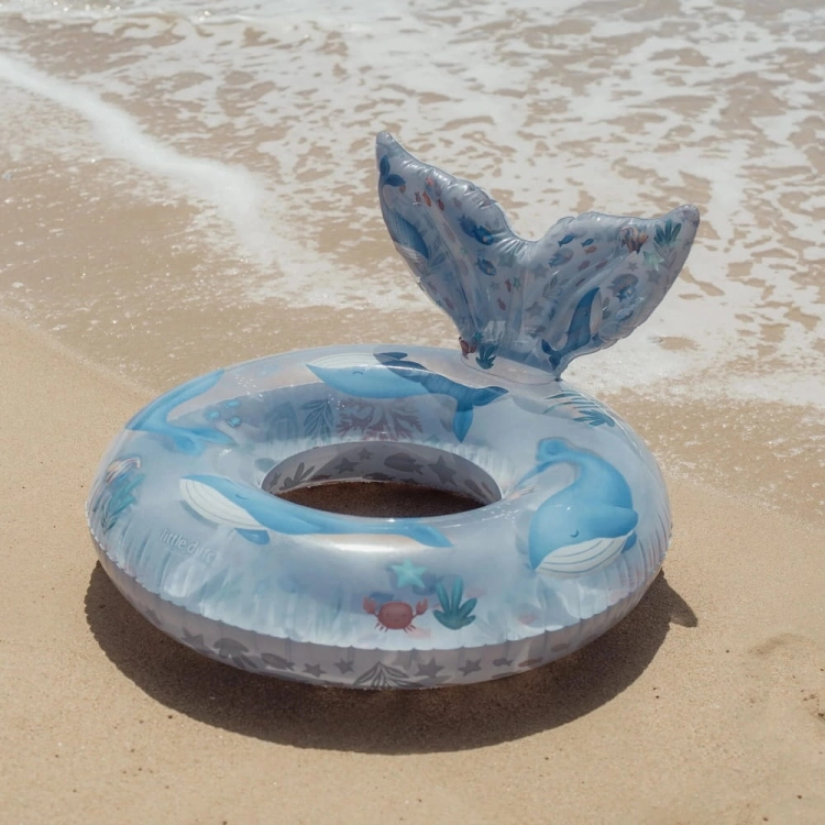 Koło do pływania Ocean World Little Dutch 91cm leżące na plaży przy fali – transparentne koło z wielorybem i ogonem