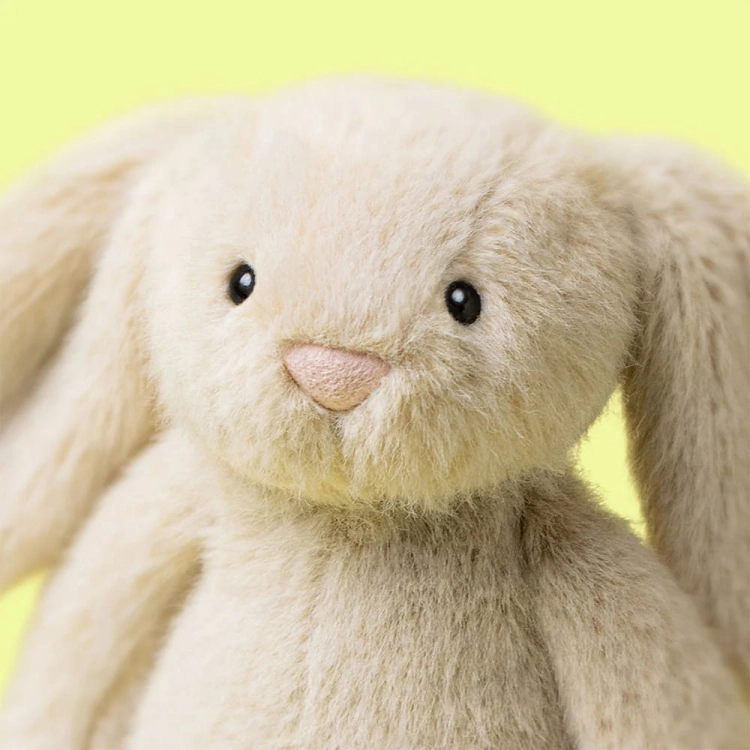 Zbliżenie na twarz przytulanka Króliczek Flufflet 18cm wheat Jellycat – kremowy nosek i czarne oczka, miękka maskotka na żółtym tle