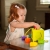 Dziewczynka wkładająca kształt do sortera OombeeCube Fat Brain Toys – kolorowa kostka sensoryczna rozwijająca motorykę małą u niemowląt