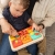 Tablica PlayTab Fat Brain Toys – chłopiec siedzący na kolanach rodzica bawi się zestawem kolorowych paneli aktywności z labiryntem, guzikami i kuleczkami, zabawka edukacyjna stymulująca zmysły