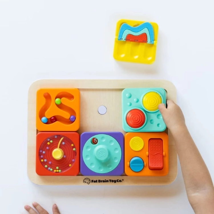 Tablica PlayTab Fat Brain Toys – widok z góry na drewnianą podstawę z 5 zamontowanymi panelami sensorycznymi w różnych kolorach, jeden żółty panel odłożony obok, logo Fat Brain Toy Co., zabawka dla niemowląt