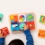 Tablica PlayTab Fat Brain Toys – widok z góry na dziecko bawiące się pełnym zestawem paneli aktywności ułożonych na drewnianej podstawie, wokół rozłożone dodatkowe panele, zabawka rozwijająca koordynację ruchową