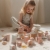 Zestaw klocków Fairy Garden FSC Little Dutch – dziewczynka siedząca na dywanie i skupiona na układaniu różowych drewnianych klocków z motywem wróżek