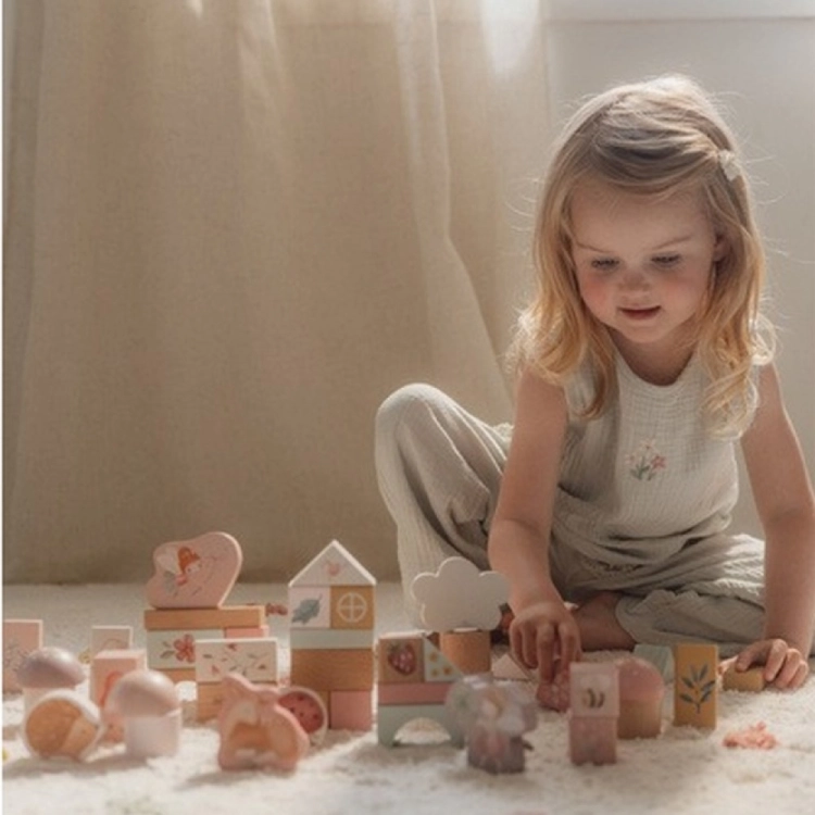 Zestaw klocków Fairy Garden FSC Little Dutch – dziewczynka przy oknie układa bajkowe różowe klocki z domkiem, chmurką i figurkami na białym dywanie