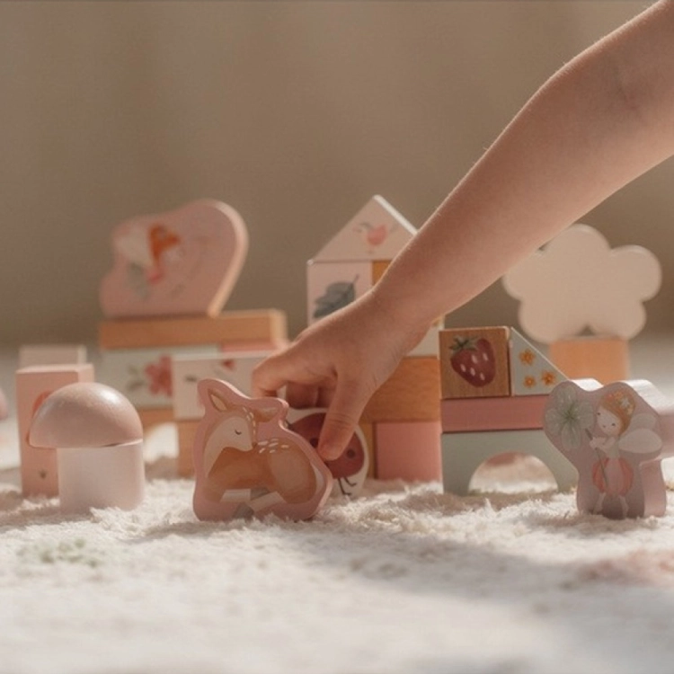 Zestaw klocków Fairy Garden FSC Little Dutch – dłoń dziecka sięgająca po figurkę jelonka wśród różowych klocków z jeżykiem, grzybkami i domkiem