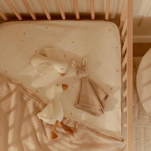 Zestaw prezentowy Dzianinowy Newborn Naturals Little Dutch – widok z góry na łóżeczko z dzianinową gęsią i przytulanką królikiem na pościeli w złote księżyce