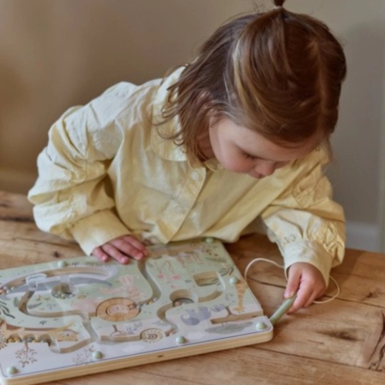 Dziewczynka w żółtej koszuli przesuwa rysikiem kulki w labiryncie magnetycznym Little Dutch Safari Friends