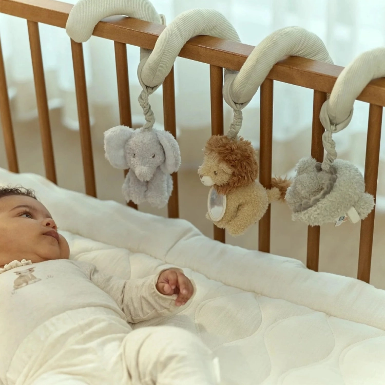 Spiralka aktywizująca Little Dutch Safari Friends owinięta wokół szczebelków łóżeczka, niemowlę patrzy na maskotki