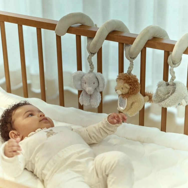 Niemowlę w łóżeczku wyciąga rękę do maskotek spiralki aktywizującej Little Dutch Safari Friends