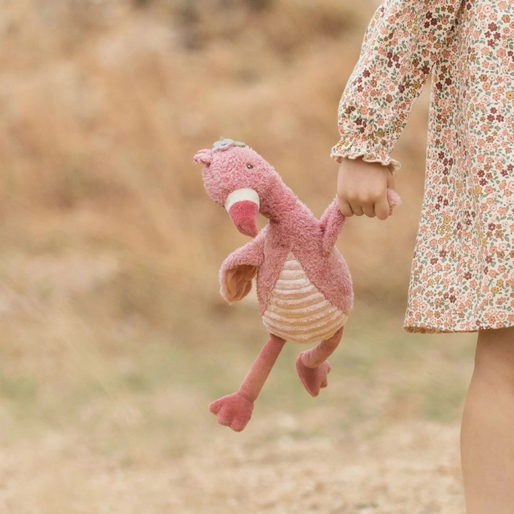 Dziewczynka niesie przytulankę flaminga Little Dutch Safari Friends trzymając ją za skrzydło