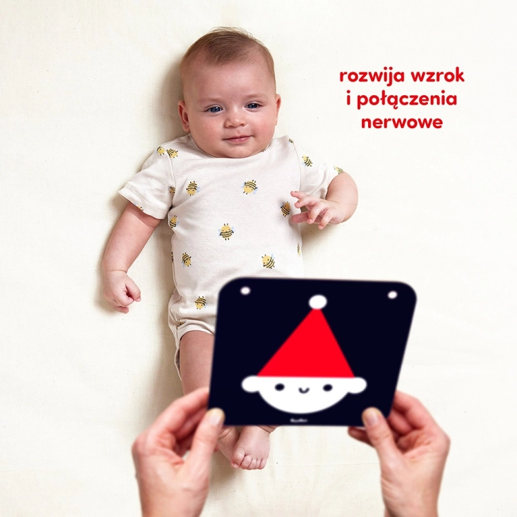 Niemowlę leżące na plecach patrzy na kartę kontrastową CzuCzu z czerwoną czapką