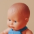 Zbliżenie na twarz lalki Miniland Baby 21 cm: niebieskie oczy i włosy wyrzeźbione w materiale lalki