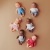 Sześć lalek Miniland Baby 21 cm o różnych karnacjach i w różnych ubrankach ułożonych obok siebie na beżowym tle