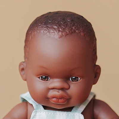 Zbliżenie na twarz lalki Miniland Baby 21 cm: brązowe oczy i krótkie kręcone włosy wyrzeźbione w materiale lalki