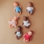 Sześć lalek Miniland Baby 21 cm w różnych strojach, w tym dziewczynka w malinowej sukience i bordowej opasce