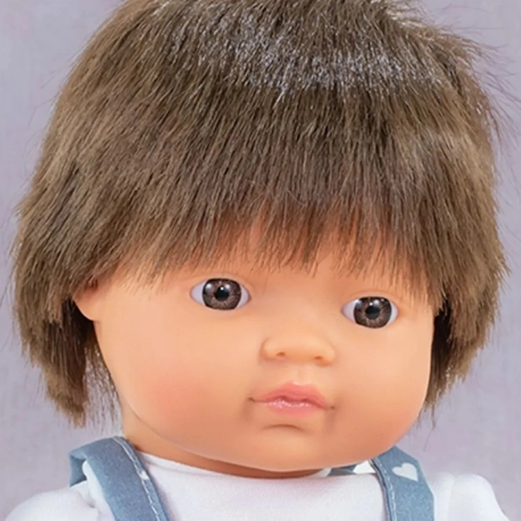 Zbliżenie na twarz lalki Miniland 38 cm: gęste brązowe włosy z grzywką i brązowe oczy