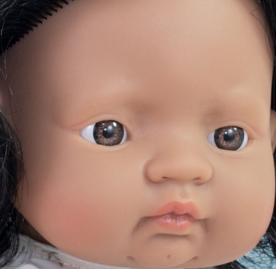 Zbliżenie na twarz lalki Miniland 38 cm: brązowe oczy, ciepła karnacja i czarne włosy
