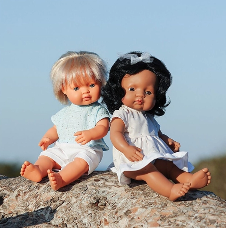 Dwie lalki Miniland My Friends & Me 38 cm siedzące na pniu drzewa: dziewczynka z czarnymi falowanymi włosami i chłopiec blond