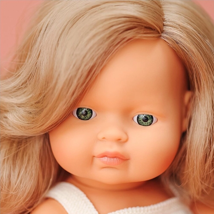 Zbliżenie na twarz lalki Miniland 38 cm: zielone oczy i długie, falowane ciemne blond włosy